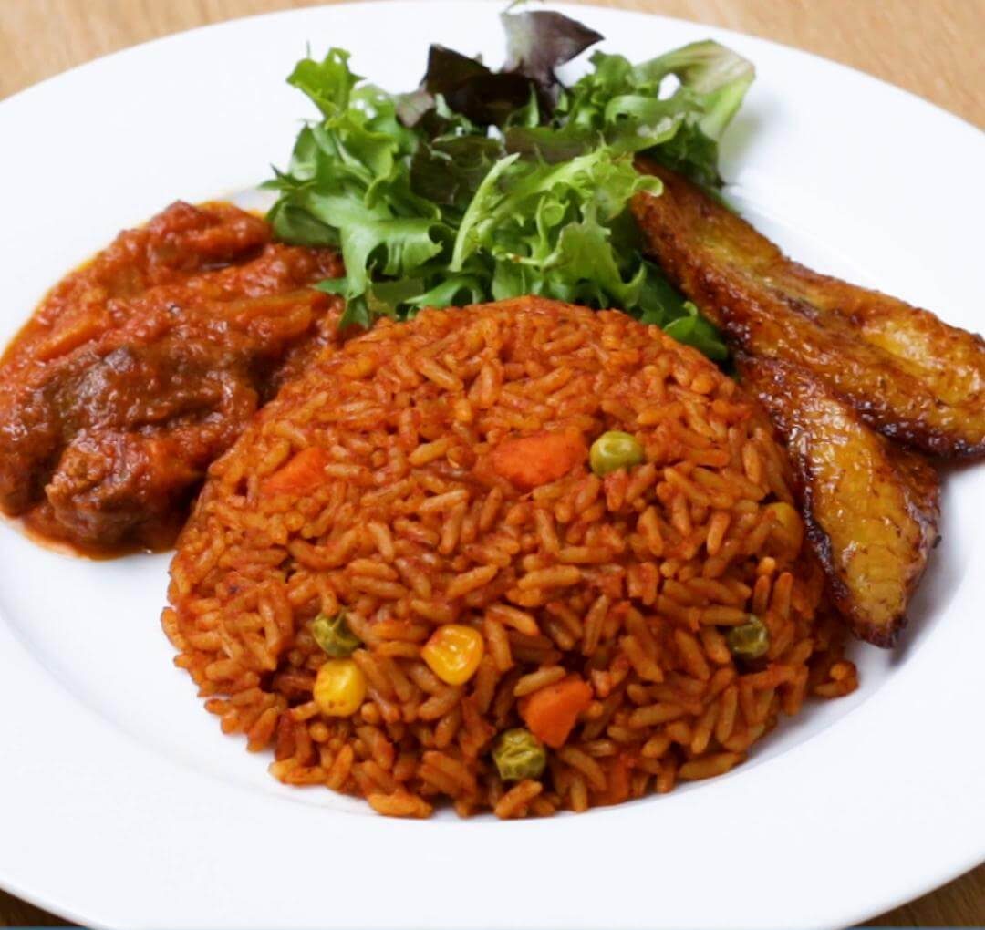 Top view of delicious smoky Nigerian Jollof Rice with plantain and chicken